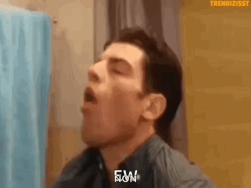 Man Yawning in Front of Blue Shower Curtain