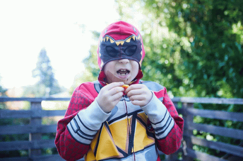 Masked Boy Eating Snack In Red Hoodie GIF