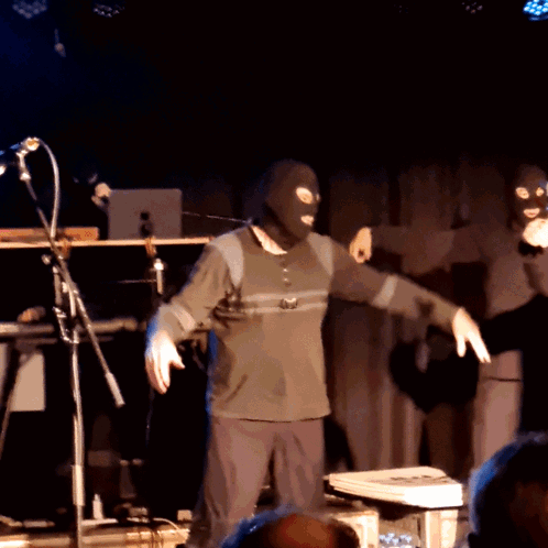 Masked Man Dancing on Stage with Microphone