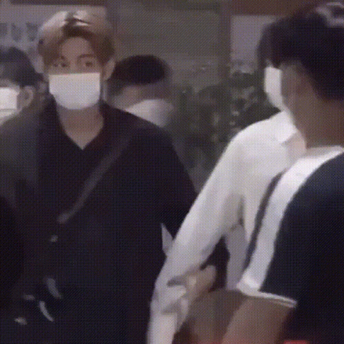 Masked Man Holding Another's Hand in Crowd