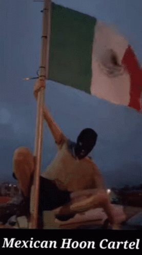 Masked Man Holding Mexican Flag With Mexican Hoon Cartel Sign