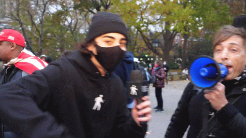 Masked Man Holding Microphone Woman Shouting into Megaphone