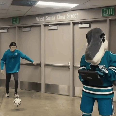 Masked Man Kicking Soccer Ball Beside Mascot with Tablet