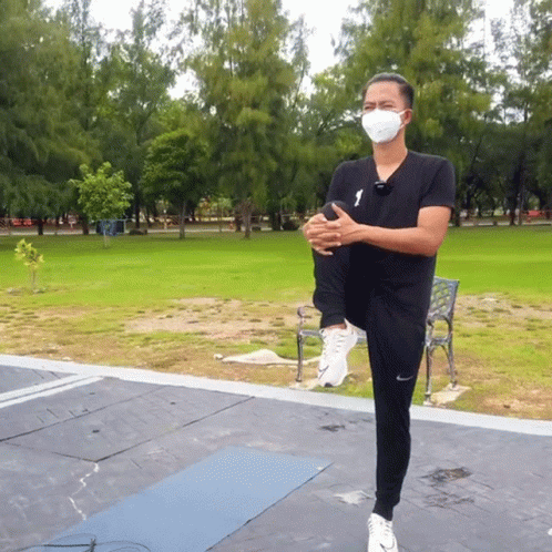 Masked Man Stretching Leg in Park