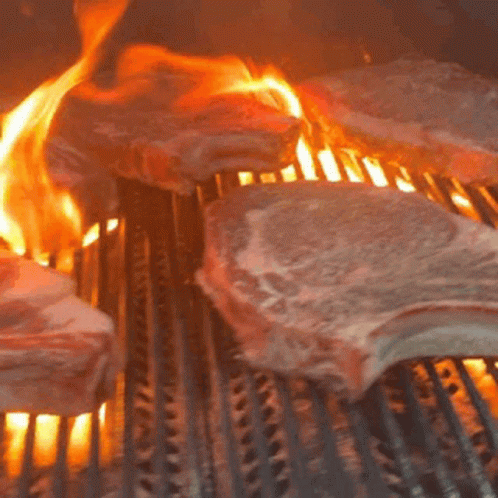 Meat Is Being Cooked On A Grill With Flames Coming Out Of It GIF