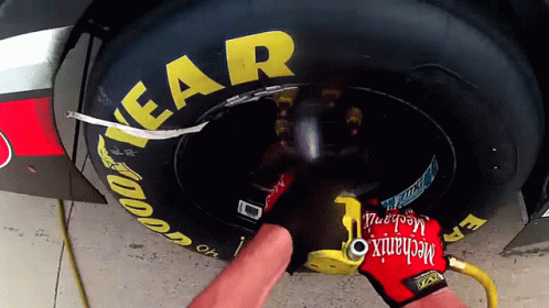 Mechanic Wearing Red Glove Working on Race Car Tire