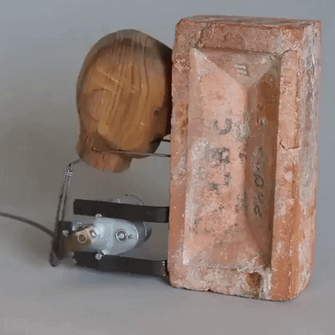 Mechanical Wooden Structure Banging Head Against Wall GIF