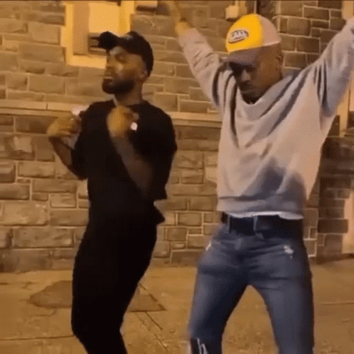 Men Dancing in Front of Brick Wall