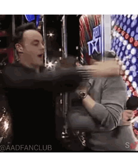 Men Hugging in Front of Americas Got Talent Sign