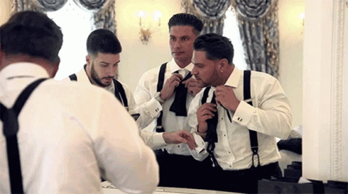 Men in Tuxedos and Suspenders Getting Ready in Front of Mirror