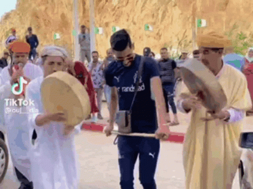 Men Playing Drums On Street For Crowd GIF