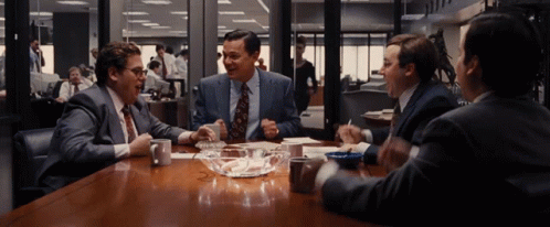 Men Sitting Around Table With Bowl of Ashes