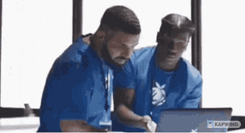 Men Sitting at Table Looking at Laptop
