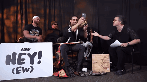Men Sitting in Front of Hey (Ew) Sign