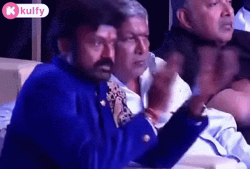 Men Sitting In Row, One In Blue Jacket Tie GIF