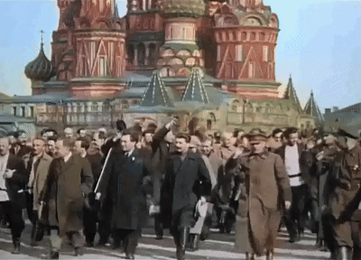 Men Walking In Front Of Red Building GIF