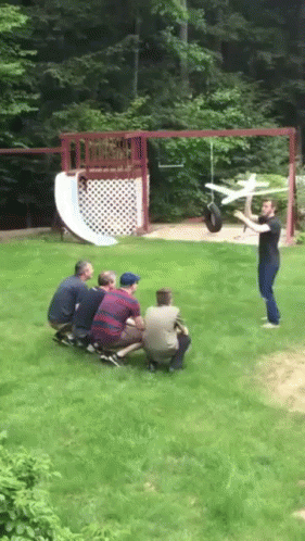 Men Watching Man Throwing Toy Airplane