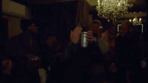 Men Waving Bottles in Dark Room