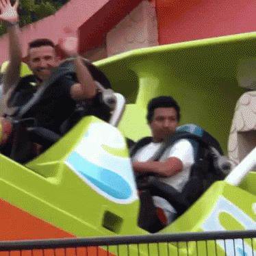 Men Waving While Taking Rides In Disneyland GIF