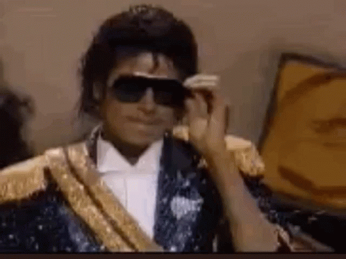 Michael Jackson Is Wearing Sunglasses And A Tuxedo . GIF