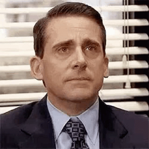 Michael Scott From The Office Is Wearing A Suit And Tie And Looking At The Camera . GIF