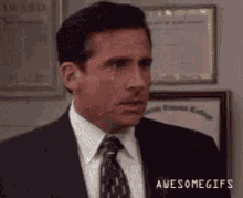 Michael Scott From The Office Is Wearing A Suit And Tie And Making A Funny Face . GIF
