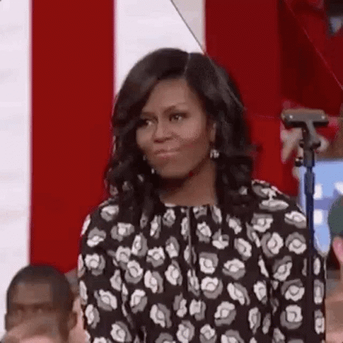 Michelle Obama Is Standing In Front Of A Microphone In Front Of A Crowd . GIF