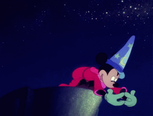 mickey mouse wearing a wizard hat is crawling on a cliff