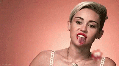 Miley Cyrus Is Sticking Her Tongue Out While Holding A Lollipop . GIF