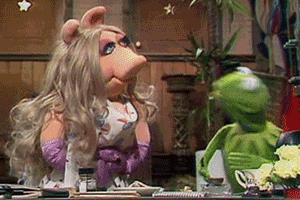 Miss Piggy And Kermit The Frog Are Sitting At A Table In A Kitchen . GIF
