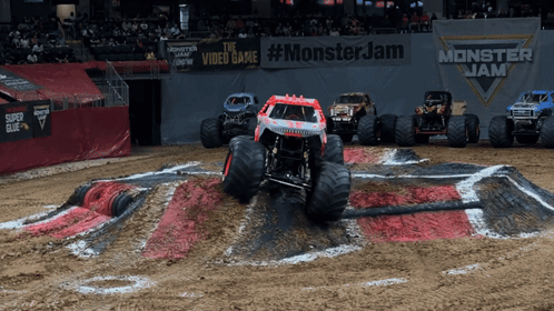 Monster Jam Sign Behind Monster Trucks on Dirt Track