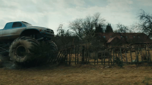 Monster Truck Driving Through Field Near Fence