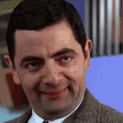 Mr Bean Is Making A Funny Face While Wearing A Suit And Tie . GIF