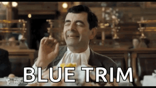mr bean is sitting at a table with a napkin around his neck and eating a sandwich .