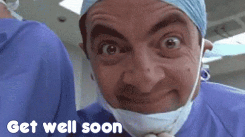 mr bean is wearing a surgical mask and a surgical gown and says get well soon