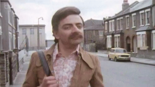 Mustached Rowan Atkinson Striding Happily GIF