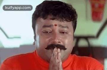 Mustached Man in Red Shirt Praying with Folded Hands