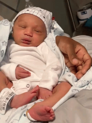 Newborn Baby Held by Person with Here Tag
