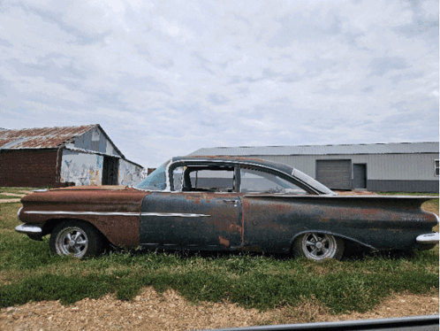 Old Rusty Car Parked in Field With Barn