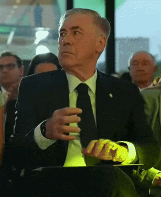 Older Man in Suit and Tie Sitting in Crowd