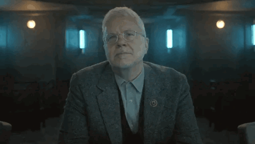 Older Man in Suit Arms Crossed Dark Room