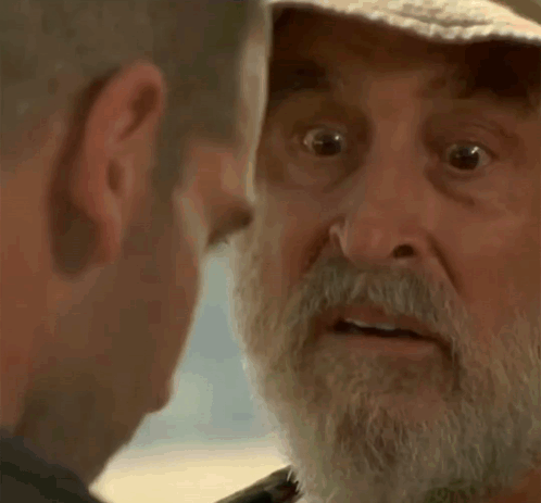 Older Man With Beard and Hat Looking at Another Man