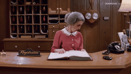 Older Woman At Reception Desk With Registration Sign GIF
