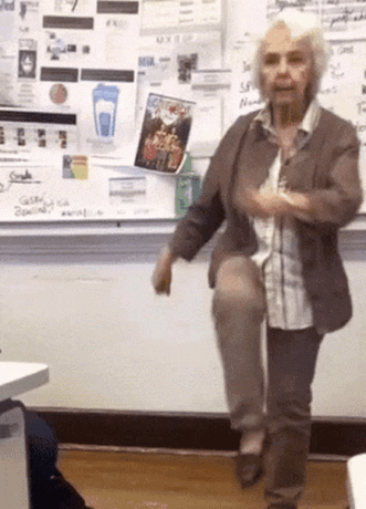Older Woman on One Leg at Whiteboard With Blue Cup
