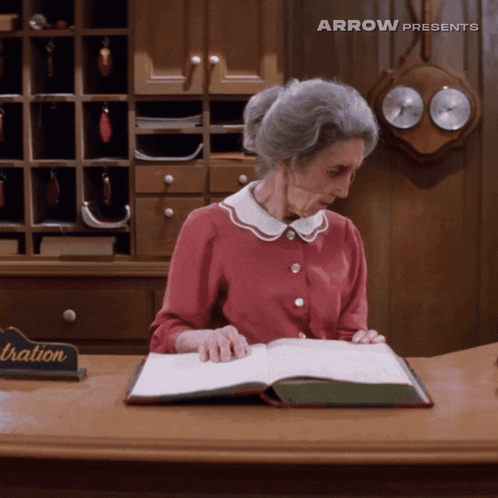 Older Woman Reading Book At Registration Desk GIF
