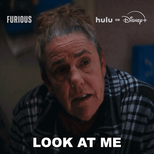 Older Woman Says Look at Me in Front of Furious Sign