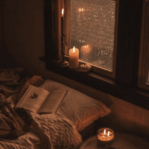 Open Book On Bed Next To Candle GIF
