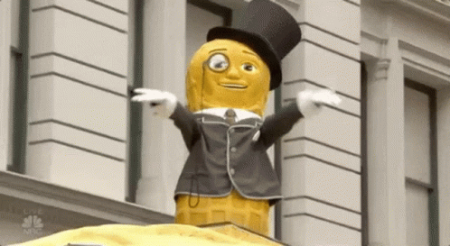 Peanut Mascot In Top Hat And Suit In Front Of Building GIF