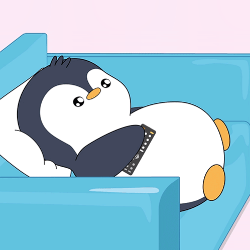 Penguin Laying on Blue Couch With Remote Control