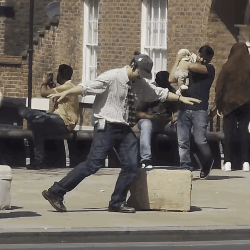 People Gathered On Sidewalk In Front Of Brick Building GIF